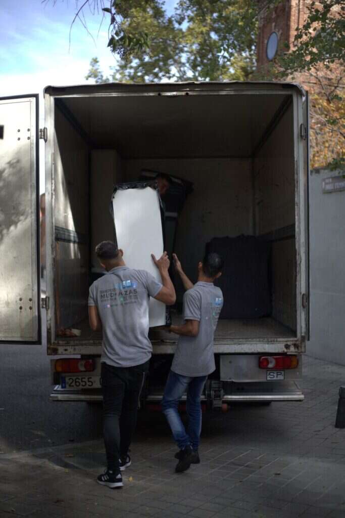 Dos operarios cargando mobiliario en el camion de mudanzas