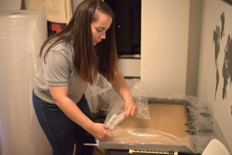 Operaria protegiendo un cuadro con plastico de burbujas